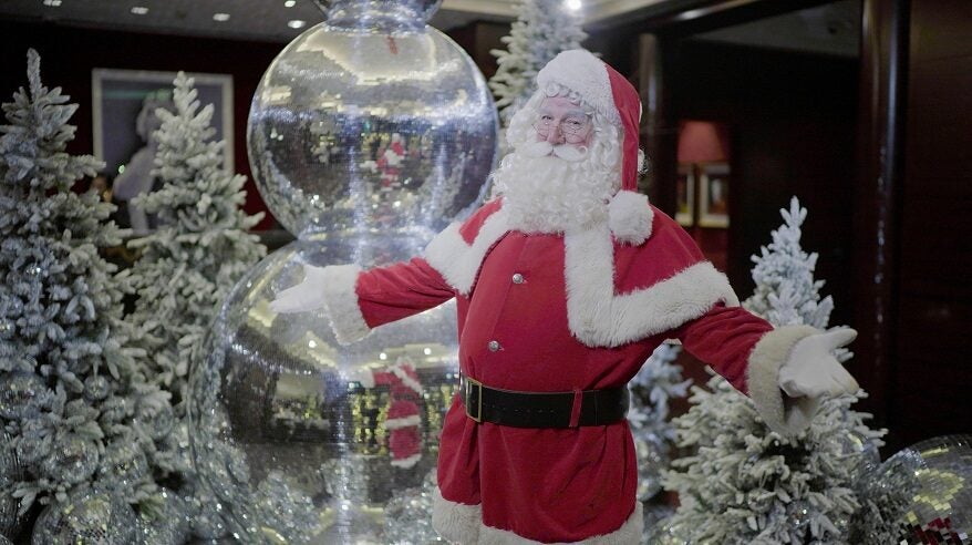 Father Christmas standing by giant baubles