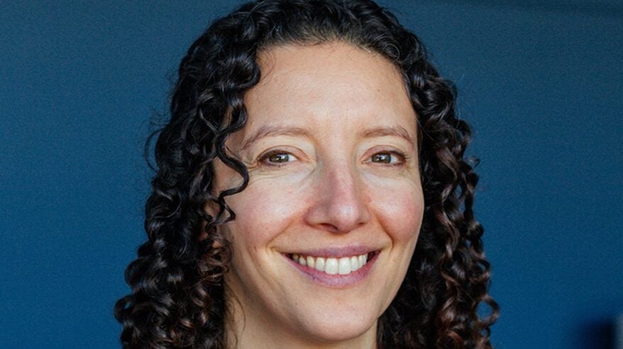 Headshot of Bianca Gavin of the PGGB, with dark curly hair, against a blue background