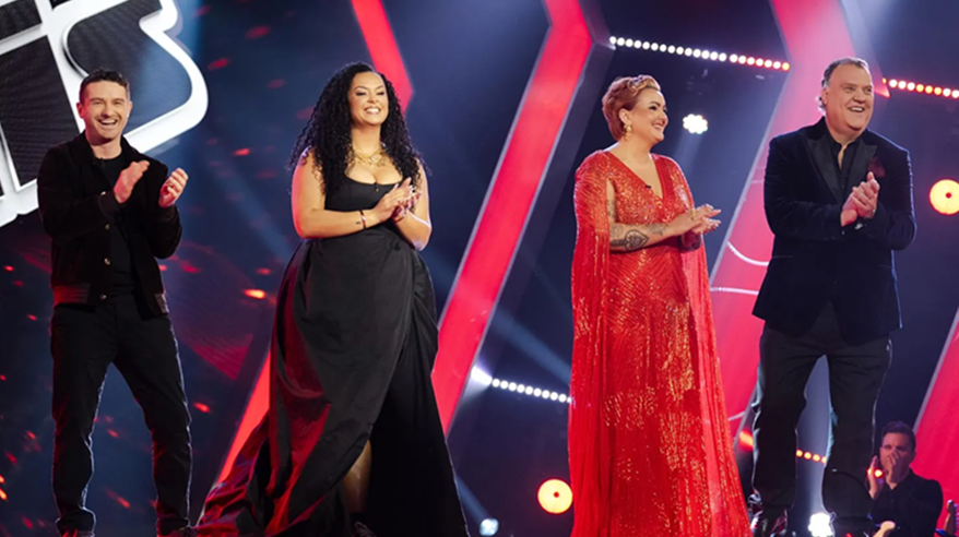 Three singers in evening wear stand on a brightly-lit sound stage
